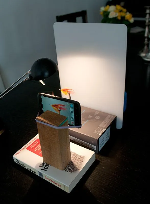 Smartphone setup - The phone is simply strapped to a wooden block using two rubber bands: one on the block to keep the phone from slipping and one to hold it. Simple, cheap and effective. The background is a nylon cutting board and the setup is built by books and cardboard boxes.